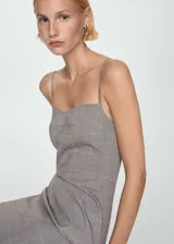 Vestido corto entallado con escote corazón y tirantes finos. Presenta un diseño estampado a cuadros en tonos grises con líneas finas en naranja.
