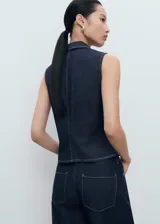 Top sin mangas estilo chaleco confeccionado en tejido de algodón y lino, con cuello solapa, cierre frontal con cremallera y costuras en contraste.