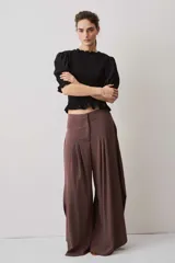 Pantalón marrón de corte ancho y fluido, con pinzas frontales y tiro alto.