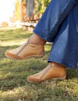 Zapatito marrón de cuero con puntera de gamuza, cierre frontal con cremallera y tirador trasero.