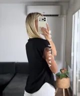 Blusa negra de tela Cey, con cuello mao y escote en V con cierre. Mangas cortas con detalle de encaje marrón en los hombros.