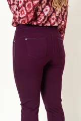 Calza color borgoña con cintura alta, sin cierre, con falsos bolsillos delanteros y bolsillos traseros con detalle de vivo de cuero en bolsillos y laterales.