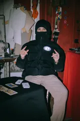 Campera puffer negra con capucha y cierre frontal. Tiene un logo estampado en el pecho.