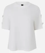 Camiseta blanca de algodón con cuello redondo y mangas cortas, decorada con pequeños lazos brillantes en los laterales de las mangas.