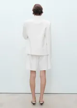 Short de denim color blanco, de tiro alto y diseño recto con cinco bolsillos, trabillas para cinto y cierre frontal con cremallera y botón.