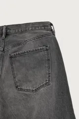 Jeans de denim de algodón color gris con efecto lavado, de corte relaxed barrel fit y tiro medio. Presenta diseño amplio con pinzas en las rodillas y costuras curvas, cierre frontal con botones y cinco bolsillos tradicionales.