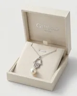 Collar de plata con cadena fina y dije en forma de mano de Hamsa decorado con circonias, acompañado por un dije de perla de río colgante.