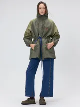 Campera tipo piloto con capucha, cierre frontal con botones y detalle de costuras en zigzag. Presenta cordones ajustables en la cintura y capucha, puños elásticos y logo bordado en el pecho.