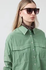 Camisa blanca de algodón con diseño utilitario y calce relajado. Presenta dos bolsillos frontales de estilo cargo con tapa y costuras a contratono.