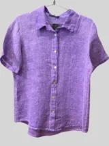 Camisa de manga corta color tostado, confeccionada en lino, con cuello camisero y cierre frontal de botones claros.