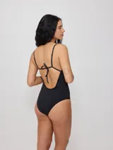 Malla entera de natación color negro con estampado de motivos playeros en blanco, con breteles finos y corte de pierna alto.