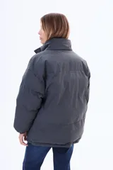 Campera puffer de corte holgado, color negro, con cuello alto, cierre frontal y puños elásticos.