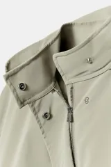 Cazadora de cuello subido con capucha ajustable, manga larga con puños elásticos y bajo elástico. Cuenta con bolsillos delanteros y cierre frontal con cremallera oculta y botones a presión.