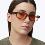 Lentes de sol con silueta rectangular, montura gruesa color camel y cristales naranjas.