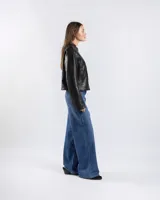 Campera de cuero sintético negro estilo motero con cuello mao, cierre frontal, bolsillos con cierre y detalles de tachas en hombros y mangas.