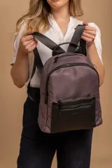 Mochila urbana de diseño combinado, confeccionada en tela de nylon color gris oscuro con bolsillo frontal y detalles en cuero sintético negro. Cuenta con compartimento principal con cierre, bolsillo frontal con cierre, correas ajustables y manija superior.