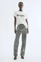 Remera de algodón blanca con cuello redondo, mangas cortas y estampa frontal con la frase "À la recherche de la beauté. Un regard suffit" en tipografía negra.