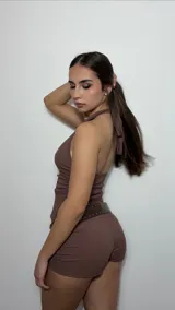 Conjunto de dos piezas color marrón, compuesto por un top sin mangas de cuello alto y un short ajustado. Ambas prendas presentan una textura rugosa y el conjunto se complementa con un cinturón de cuero marrón con tachas metálicas.