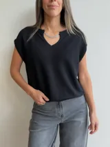 Tejido de punto de manga corta en color blanco, con escote en V y detalle de cadena metálica desmontable en el cuello. Presenta un diseño holgado y textura acanalada fina.