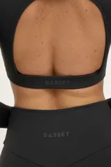 Top deportivo manga larga color gris oscuro, de escote redondo y espalda abierta.