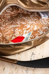 Bandolera color bronce con diseño acolchado, correa de tela regulable en color negro y monedero colgante con estampado de piel de serpiente.