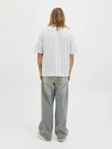 Camisa de manga corta estilo resort, confeccionada en tejido jersey de punto con diseño de rayas verticales en tonos crudo y azul. Presenta cuello camisero y cierre frontal con botones.