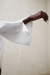 Blusa de lino blanca de corte amplio, con escote en V, mangas largas y puños con abertura y lazo.