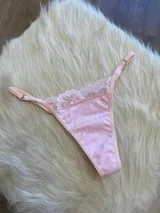 Tanga de algodón color rosa, con detalle de encaje en la parte superior y tiras laterales regulables.