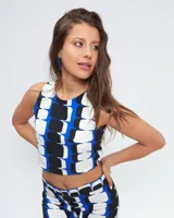 Top corto de cuello a la base y corte halter, con estampado geométrico en tonos azul, blanco y negro. Posee cierre lateral y abertura con botón en la espalda.