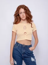 Top corto de manga corta color amarillo con estampado de lunares blancos y aberturas circulares en el escote.