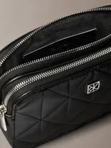 Cartera tipo bandolera Calvin Klein de diseño acolchado con patrón de rombos, color negro, cierre de cremallera y detalles metálicos plateados.
