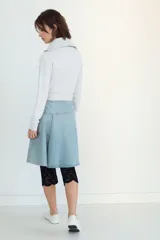 Falda midi de denim en tono azul claro, con tiro medio y diseño asimétrico con tablas laterales. Cuenta con cierre lateral mediante cremallera metálica.