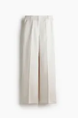 Pantalón sastrero de tiro alto y pierna recta, color blanco, con raya marcada al frente y en la espalda, bolsillos laterales al bies y bolsillos traseros decorativos.