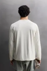 Camiseta de entrenamiento de manga larga y cuello redondo, confeccionada en tejido técnico ligero y elástico con tecnología de secado rápido. Presenta costuras planas para mayor resistencia y comodidad durante el movimiento, con un pequeño logo estampado en el bajo.