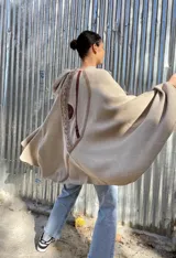 Capa color beige de tejido de punto en lana con apliques en cuero y diseño asimétrico.