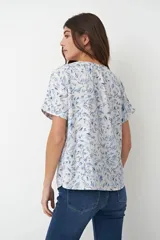 Blusa blanca con estampado floral celeste, escote en V y mangas cortas.
