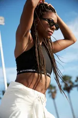 Top deportivo negro tipo halter con espalda deportiva y banda inferior con logo de la marca Lolita Activewear.