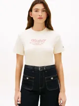 Remera de manga corta y cuello redondo color blanco marfil de Tommy Hilfiger, con el logo gráfico bordado en el pecho en tono rosado y la bandera de la marca bordada en la manga.