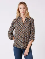 Blusa de gasa estampada con patrón geométrico en tonos azul, marrón y amarillo. Cuello a la base con detalle plisado y escote en V. Manga larga con presilla y botón para regular el largo.