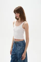Musculosa blanca de bretel ancho con cuello profundo y cierre frontal con broches.