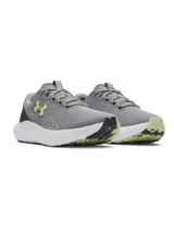 Championes de running Under Armour Charged Surge 4, color gris con detalles en verde lima y blanco. Presentan una parte superior de malla transpirable con refuerzos sintéticos, entresuela Charged Cushioning para mayor amortiguación y suela de goma resistente.
