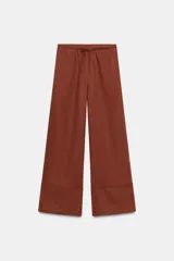 Pantalón palazzo confeccionado en hilatura de lino 100%, con cintura elástica ajustable mediante cordones y diseño de pierna ancha con dobladillo marcado en el bajo.