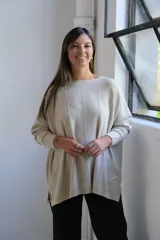 Sweater de punto con hilo lurex color beige, de corte holgado, cuello redondo y mangas largas con puños ajustados. Presenta un diseño con líneas verticales en relieve y aberturas laterales en el ruedo.