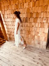 Vestido tejido color blanco con hilo metalizado, corte oversized, mangas cortas y flecos en el ruedo.