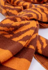 Bufanda rectangular de tejido de punto con diseño de jacquard de cebra en tonos naranja y marrón.