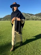 Ruana de lana merino en color tostado, con diseño de punto texturizado y terminación de flecos en el ruedo.