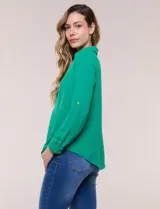 Blusa verde de calce holgado y caída fluida, confeccionada en tejido tipo crepé. Cuenta con cuello camisero con solapa, escote en V y cierre parcial al frente con tres botones metálicos. Las mangas son largas con puños abotonados.