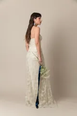 Vestido de novia strapless color natural, confeccionado en tul bordado con corsé drapeado y sobrefalda de tul. Presenta una faja con guarda en la cintura.