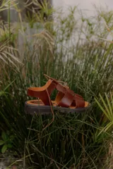 Sandalias de cuero color marrón, con diseño de tiras cruzadas, suela track y cordones finos para ajustar en el empeine.