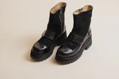 Botas negras de cuero con caña media, plataforma y hebilla decorativa.